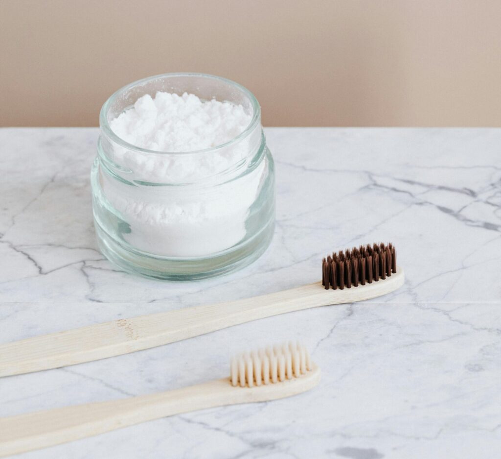 Zero-waste dental care setup with bamboo toothbrushes and toothpowder on marble.